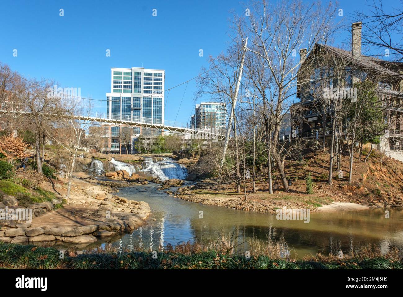 Falls Park on the Reedy mit Blick auf die Liberty Bridge und die Gebäude im Stadtzentrum von Greenville, South Carolina. Stockfoto