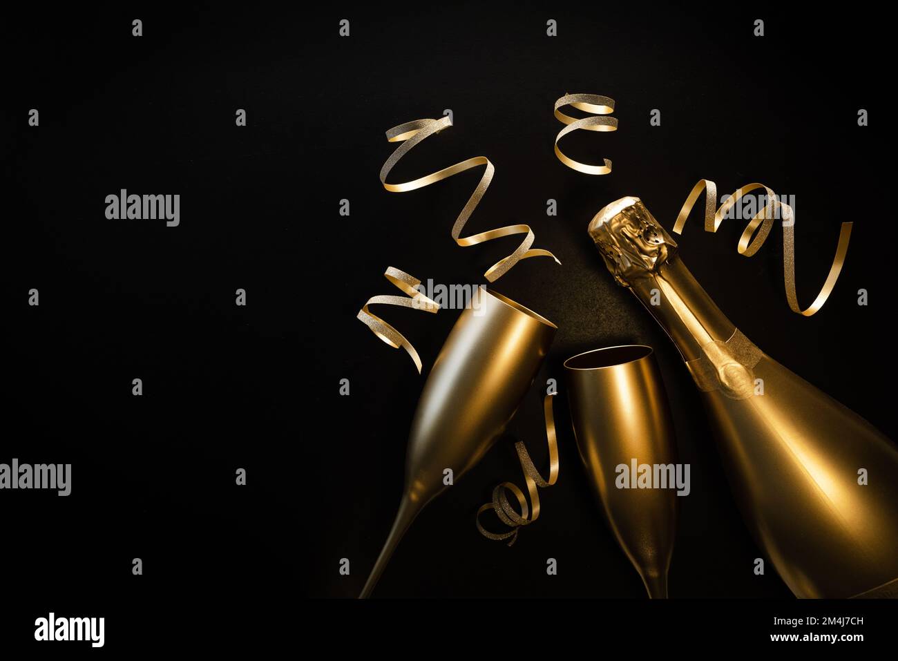goldene Champagnerflasche und zwei Gläser mit Bändern auf schwarzem Hintergrund und Kopierbereich. Silvester und Jubiläumsfeier Stockfoto