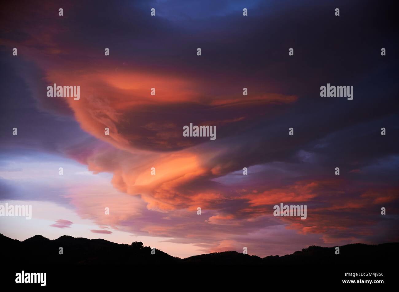 Sonnenaufgang mit einem Himmel voller wunderschöner Wolken mit Blau- und Orangenfarben, die einen Wirbel bilden Stockfoto