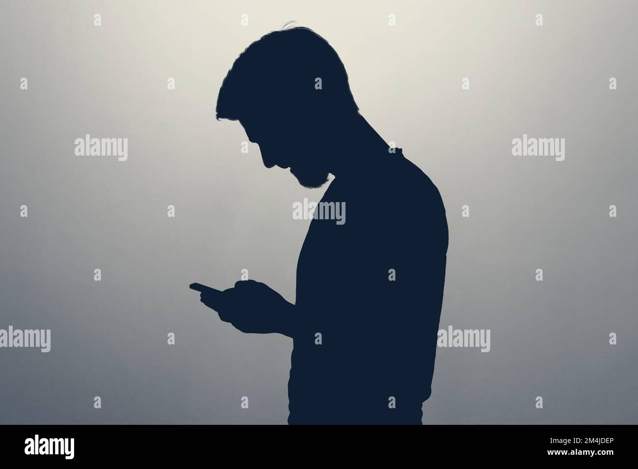 Männliche Silhouette, die auf den Bildschirm eines Smartphones schaut Stockfoto