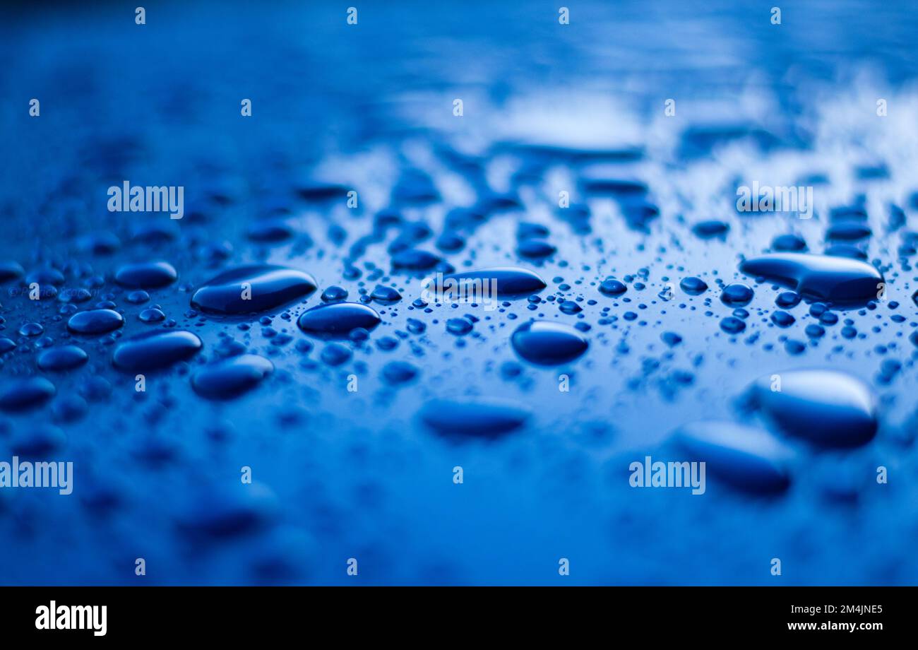Blaues Wasser tropft auf eine blaue Oberfläche Stockfoto