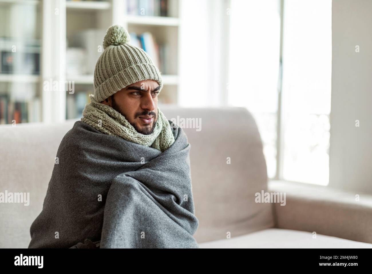 Eiskalter Typ aus dem Nahen Osten, der auf der Couch im Wohnzimmer sitzt Stockfoto