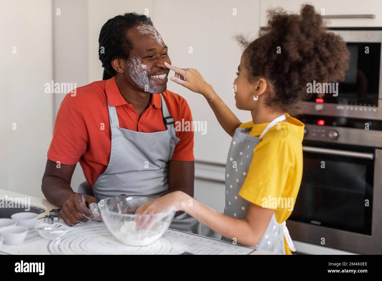 Fröhliche Beziehung Zwischen Schwarzem Vater Und Tochter, Während Wir Zusammen In Der Küche Backen Stockfoto