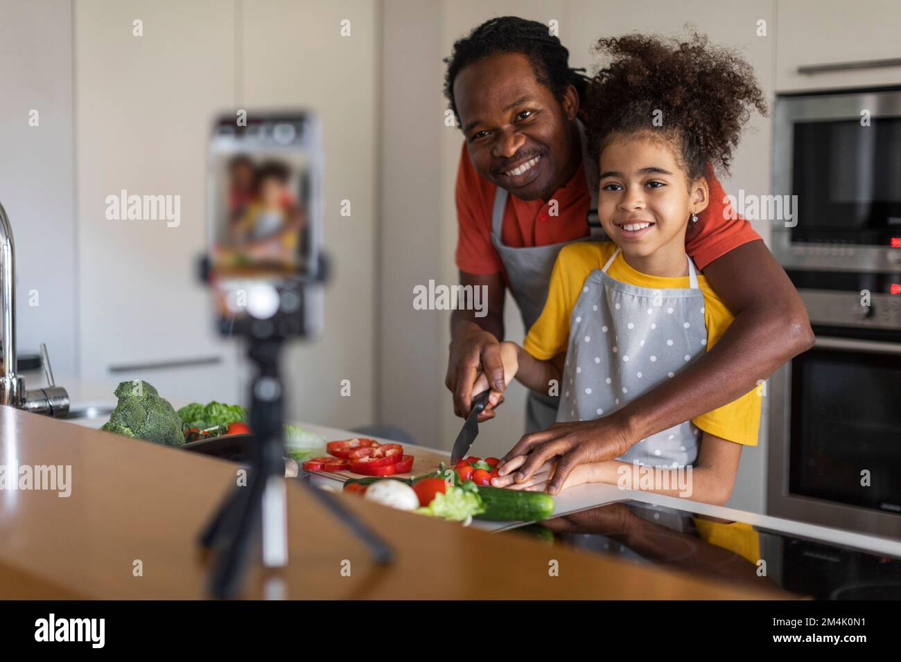 Food Blog. Schwarzer Vater Und Tochter Kochen In Camera In Kitchen Stockfoto