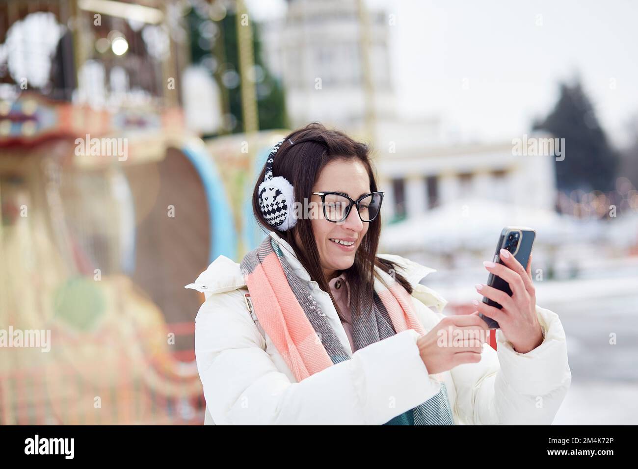 Porträt einer jungen, stilvollen Frau, die auf der Neujahrsmesse Selfie im Freien macht. Winterspaß. Gut gelaunt. Authentischer Lifestyle. Stockfoto