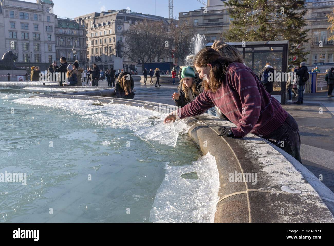 Der Brunnen am Trafalgar Square bleibt bis zum Morgen gefroren. Die Leute haben Spaß mit Eisstücken auf dem Brunnen. Aufnahme am 16. Dezember 2022. ©B Stockfoto