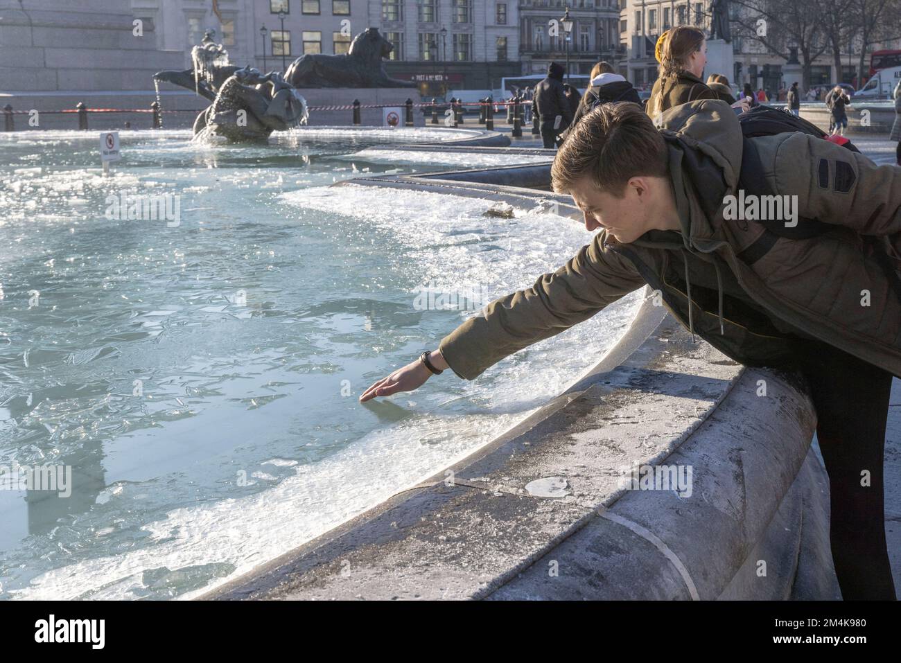 Der Brunnen am Trafalgar Square bleibt bis zum Morgen gefroren. Die Leute haben Spaß mit Eisstücken auf dem Brunnen. Aufnahme am 16. Dezember 2022. ©B Stockfoto