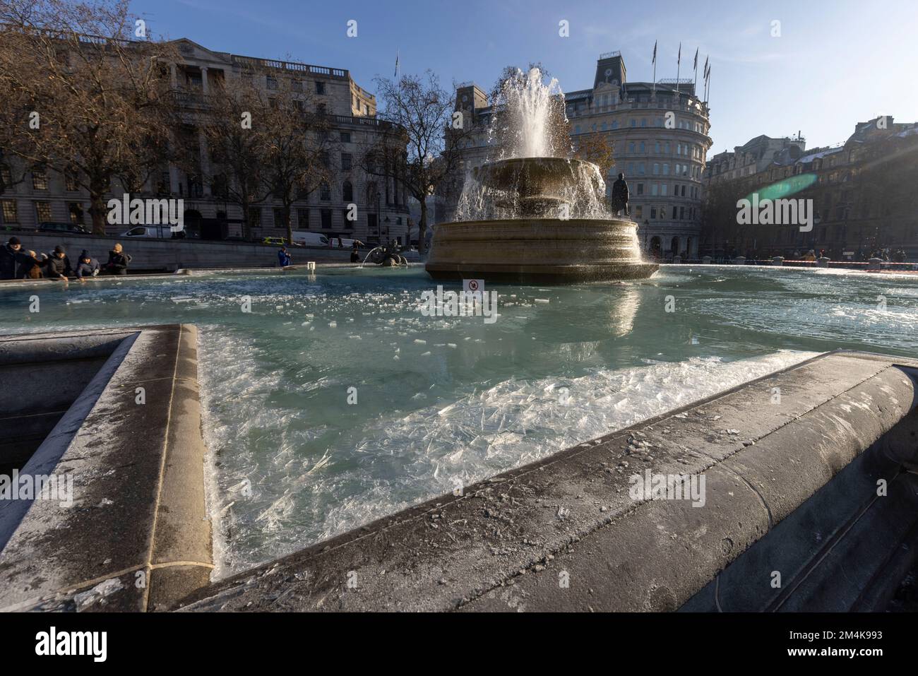 Der Brunnen am Trafalgar Square bleibt bis zum Morgen gefroren. Die Leute haben Spaß mit Eisstücken auf dem Brunnen. Aufnahme am 16. Dezember 2022. ©B Stockfoto