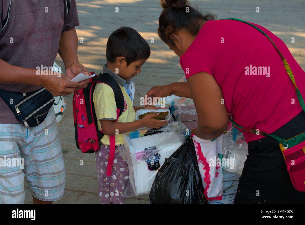 Ein Kind bekommt einen Tamal in den Straßen von Oaxaca Stockfoto