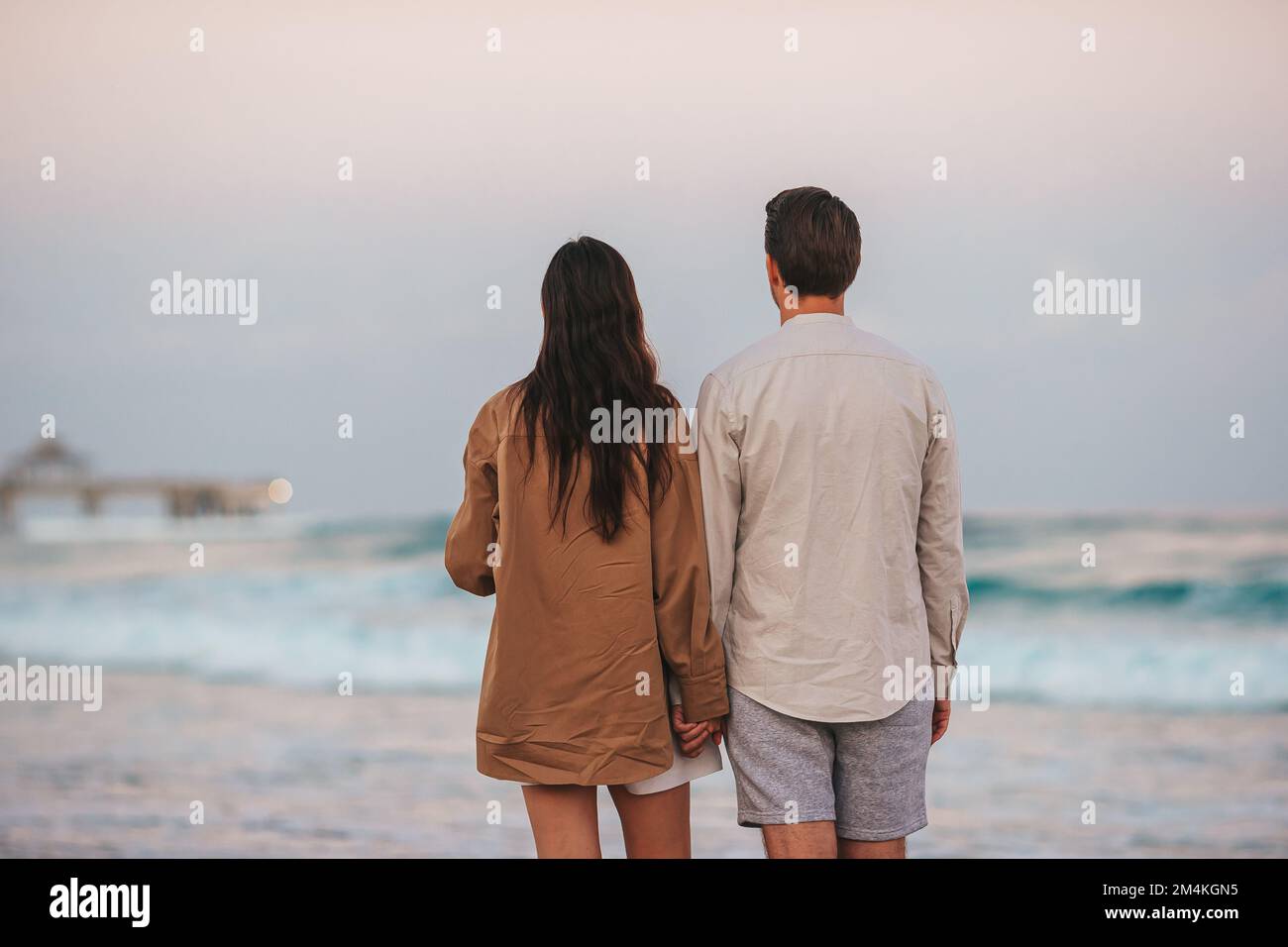 Ein junges Paar am Strand, bei Sonnenuntergang spazieren Stockfoto