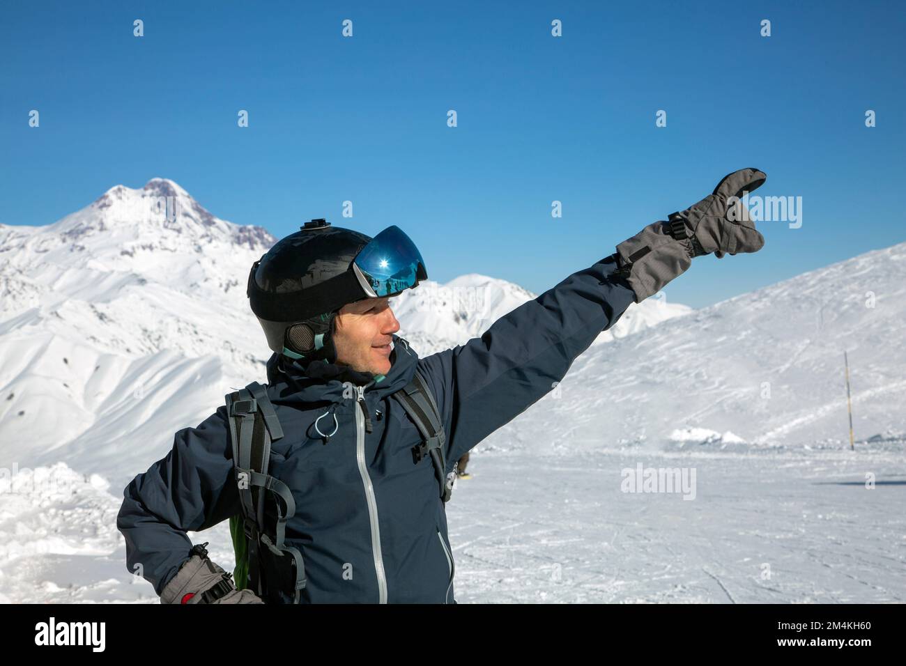 Der Kopfschuss eines fröhlichen Skifahrers zeigt die Richtung nach oben und trägt einen Skihelm und eine Schutzbrille. Gudauri, Kaukasus, Georgien Stockfoto