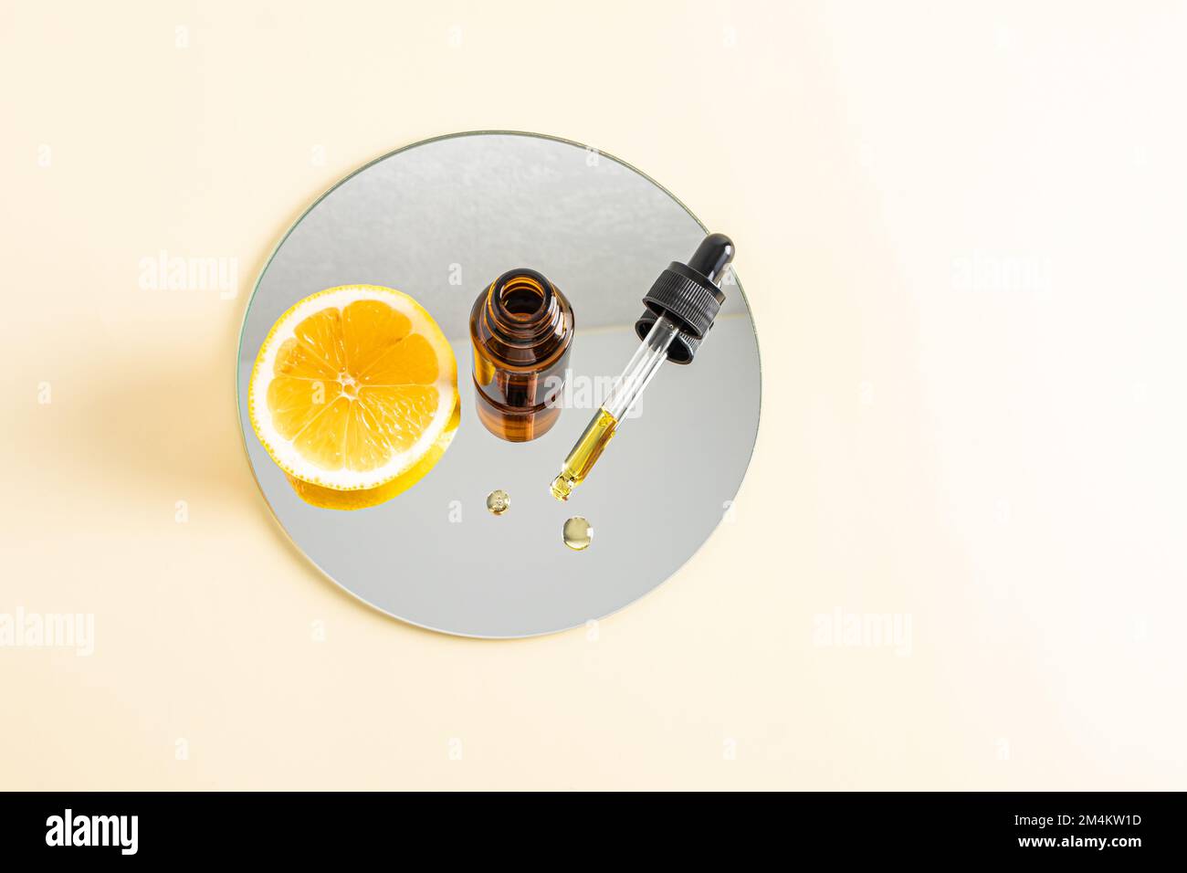 Die Befeuchtung des Serums mit Peptiden auf der Basis von ätherischem Zitronenöl zur Erhöhung der Hautelastizität, mit Vitamin C steht auf einem runden Kosmetikspiegel. Draufsicht Stockfoto