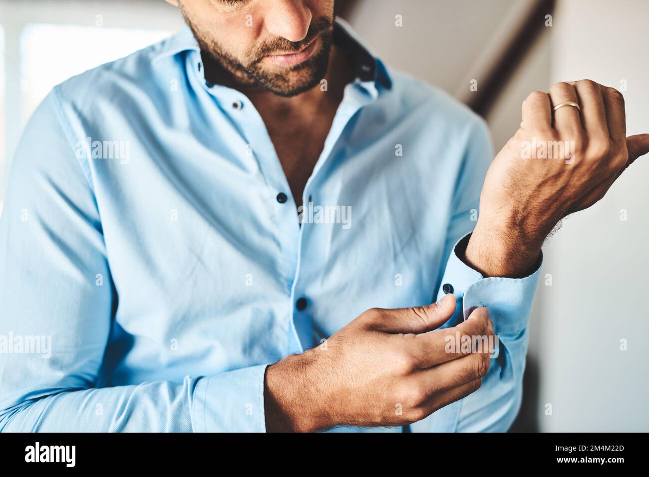 Manschettenknöpfe als nächstes. Ein unerkannter Mann, der seine Handschellen zuknöpfte, in seinem Schlafzimmer zu Hause. Stockfoto