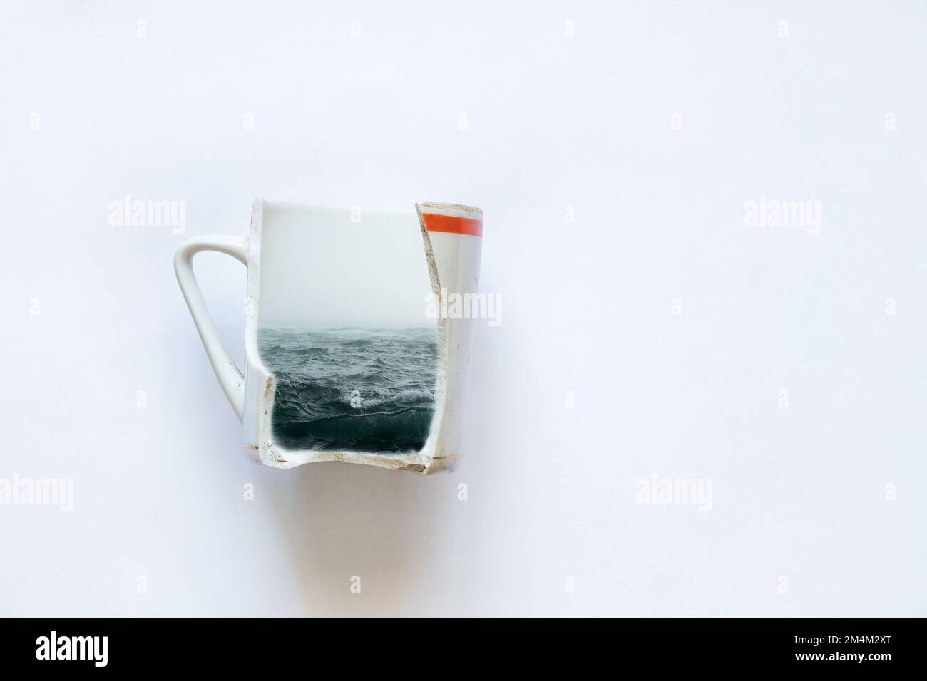 Meer in einem zerbrochenen Becher auf weißem Hintergrund Nahaufnahme, Träume vom Meer, Kreativität Stockfoto