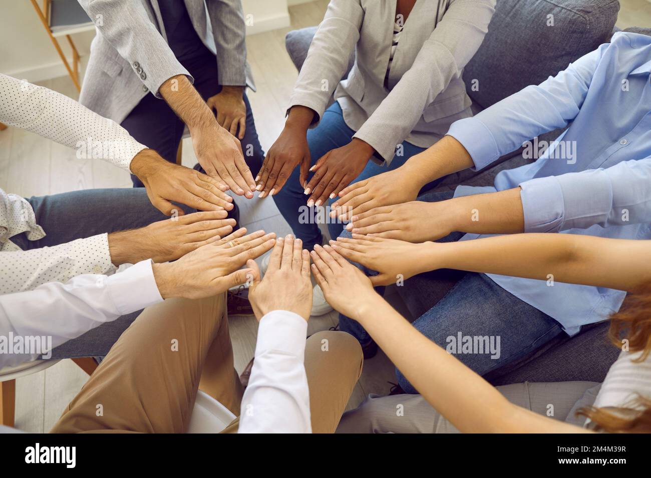 Verschiedene multirassische Männer und Frauen bilden einen Kreis, in dem ihre Hände ihre Einheit und Gleichheit zeigen. Stockfoto