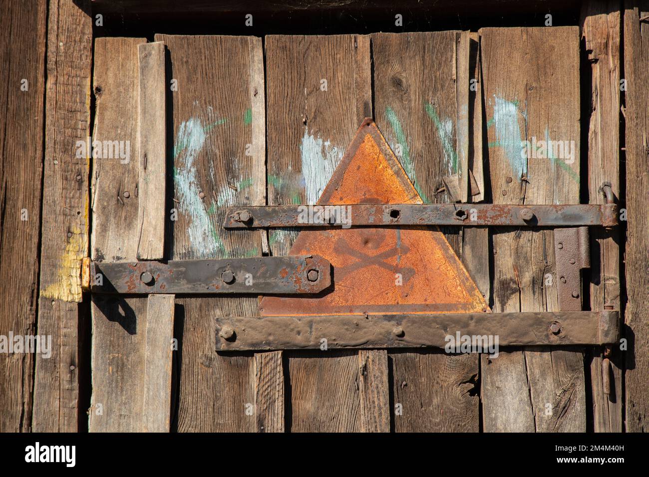 Eisenschild mit Schädel- und Knochenwarnung auf Holztür als Hintergrund Stockfoto