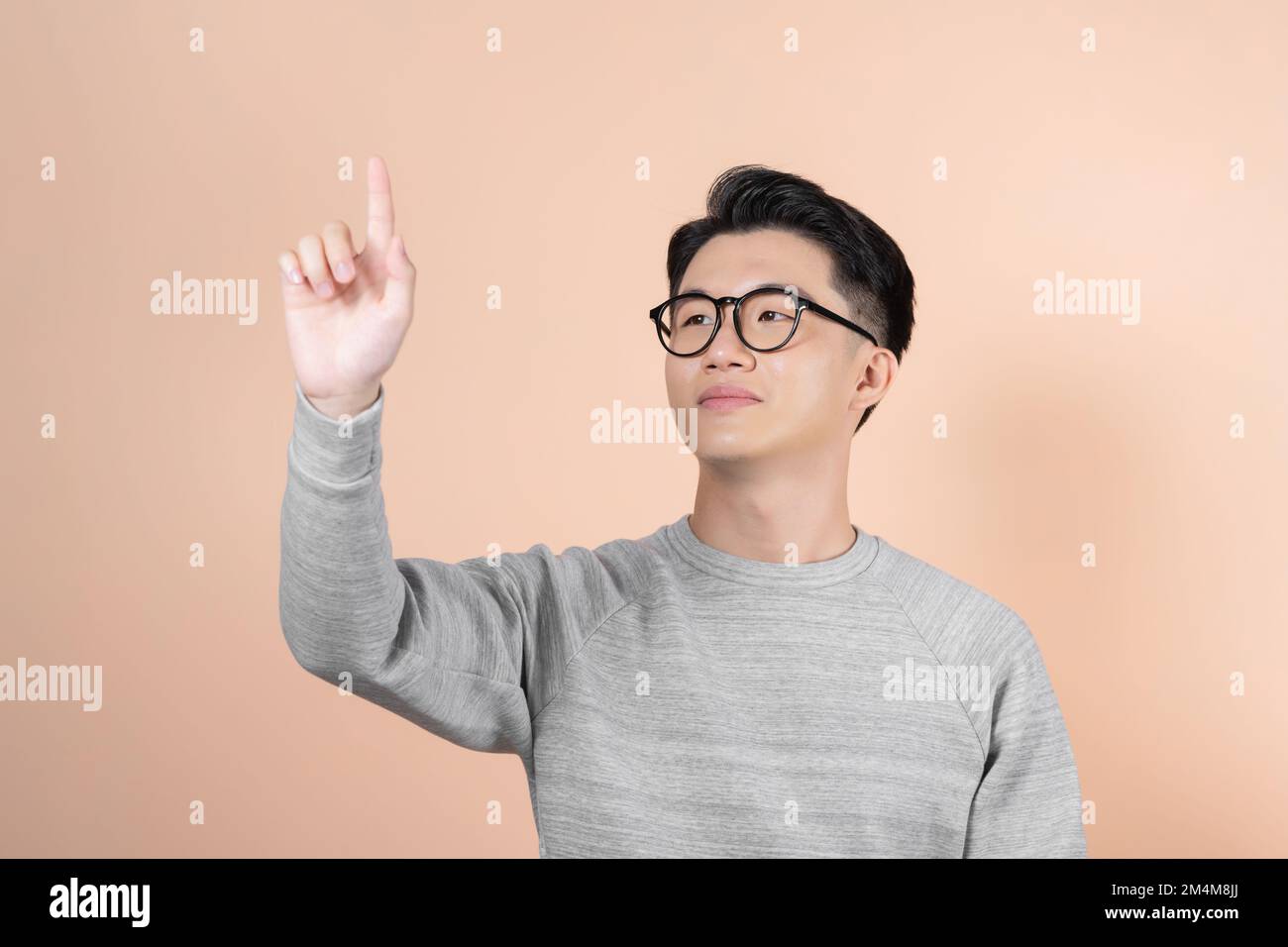 Ein klug aussehender Mann schaut nach oben und hält seine Hände, als würde er einen großen Touchscreen bedienen Stockfoto