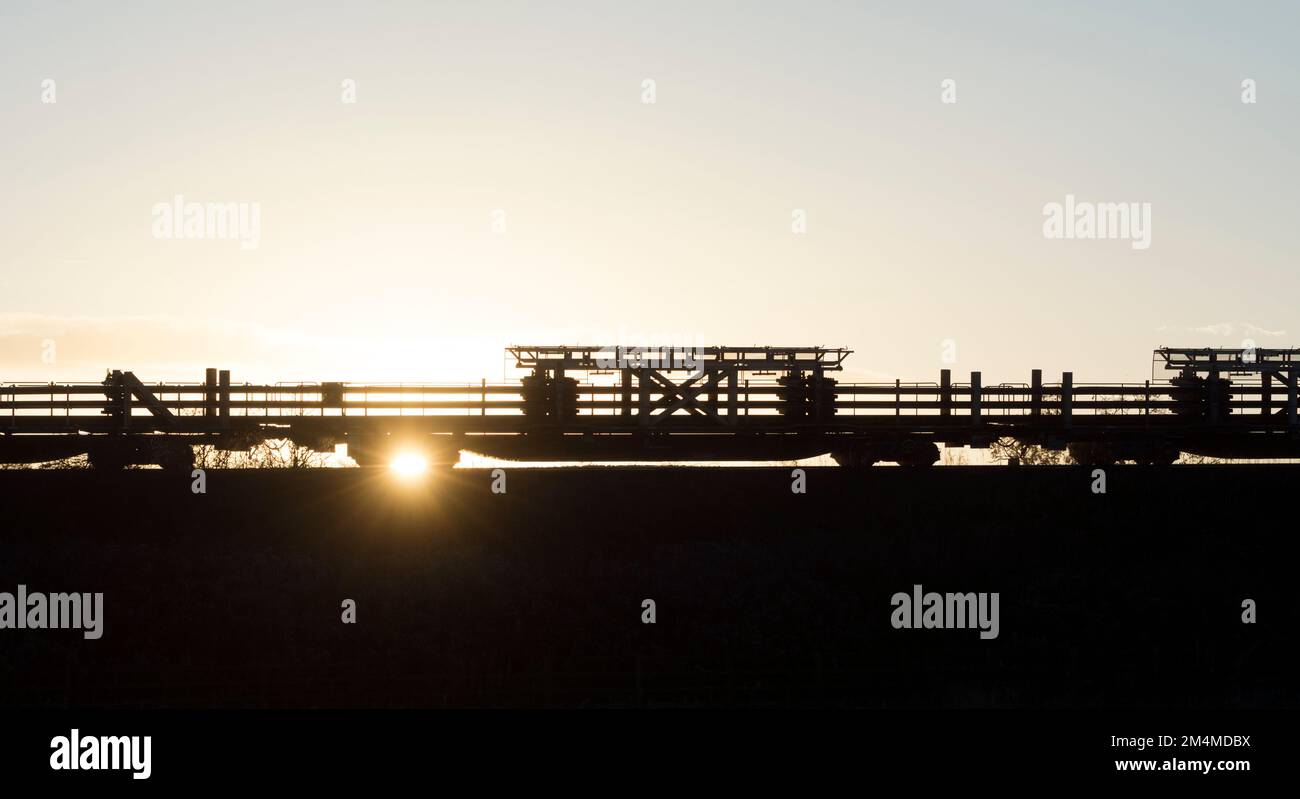 Ein langer geschweißter Schienenzug, der bei Sonnenuntergang in Warwickshire, Großbritannien, umrissen wurde Stockfoto