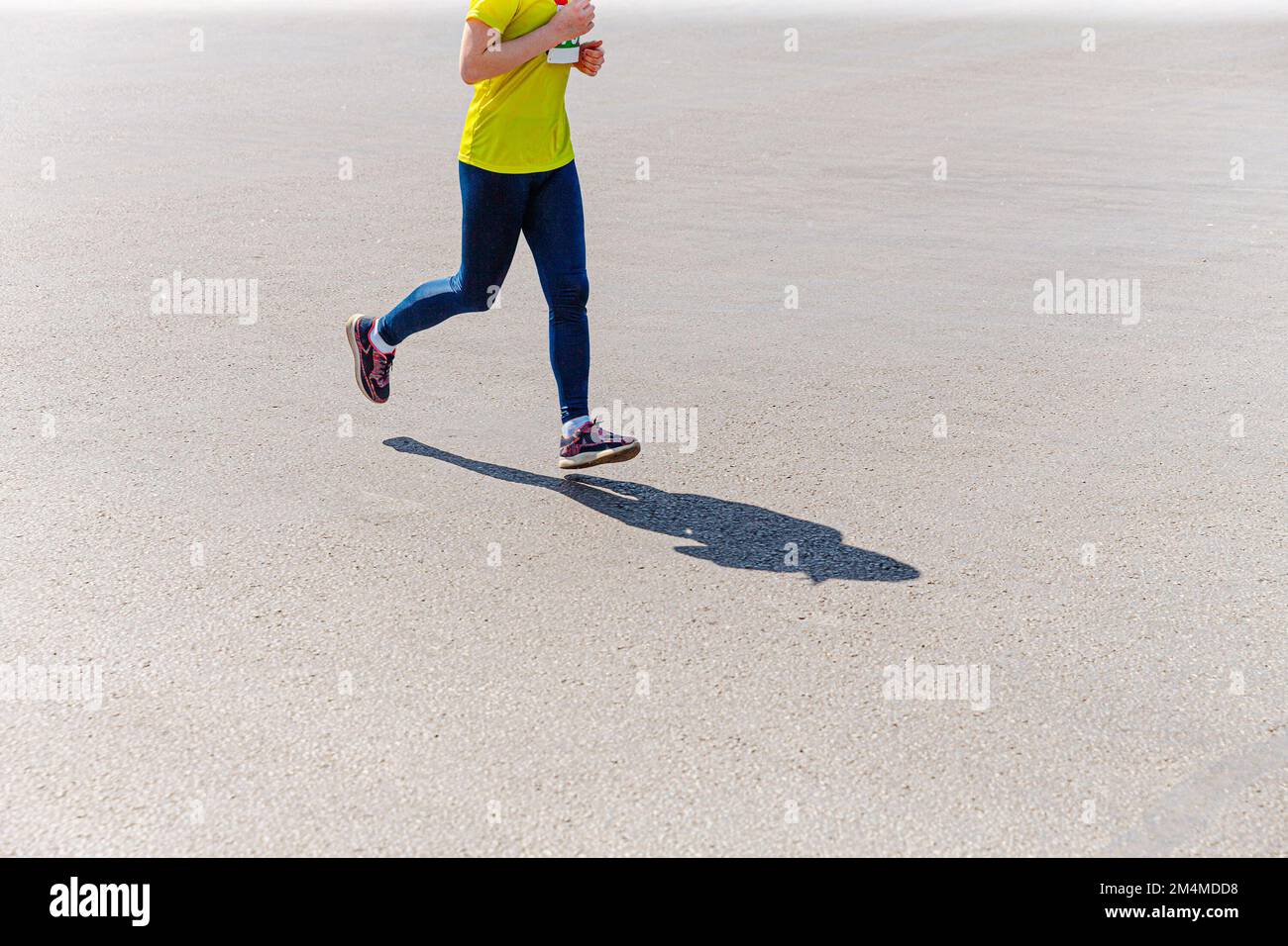 Läuferin in Leggings läuft auf Asphaltstraße Stockfoto