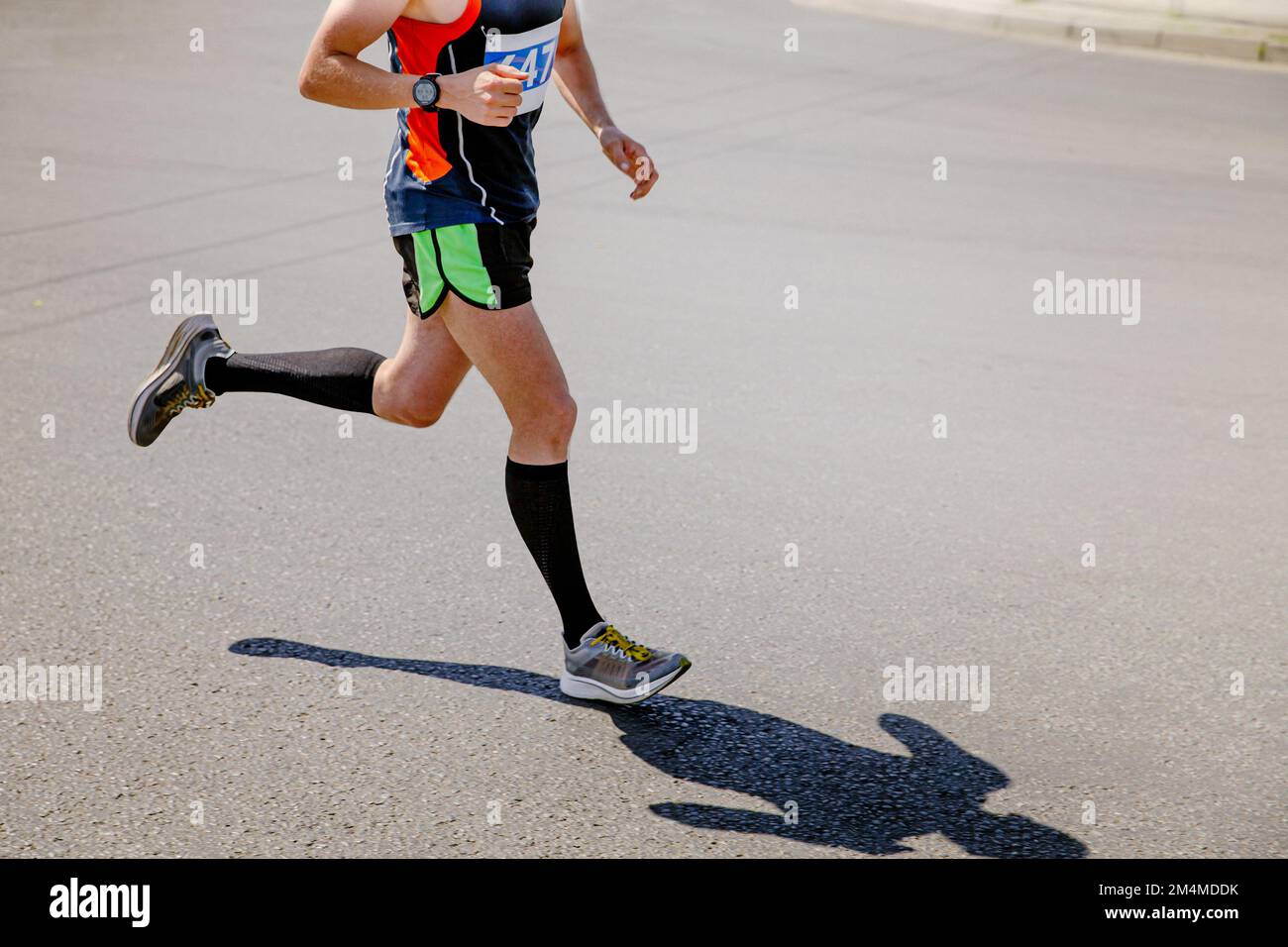 Männlicher Läufer in Kompressionssocken Rennen auf Asphalt Stockfoto