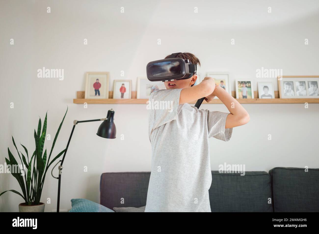 Junge, der Spaß beim Spielen von Simulationsspielen hat, mit Virtual-Reality-Headset und Controller. Kinder und modernes Technologiekonzept. Stockfoto