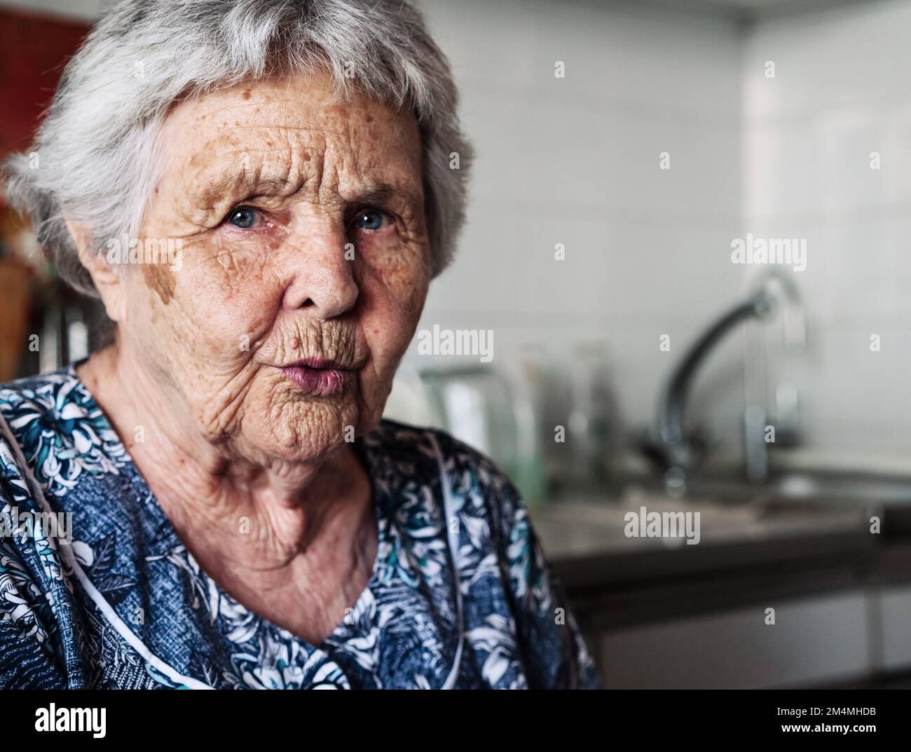 Zweiundneunzig Jahre alte weiße weiße Seniorin zu Hause, die in die Kamera schaut. Stockfoto