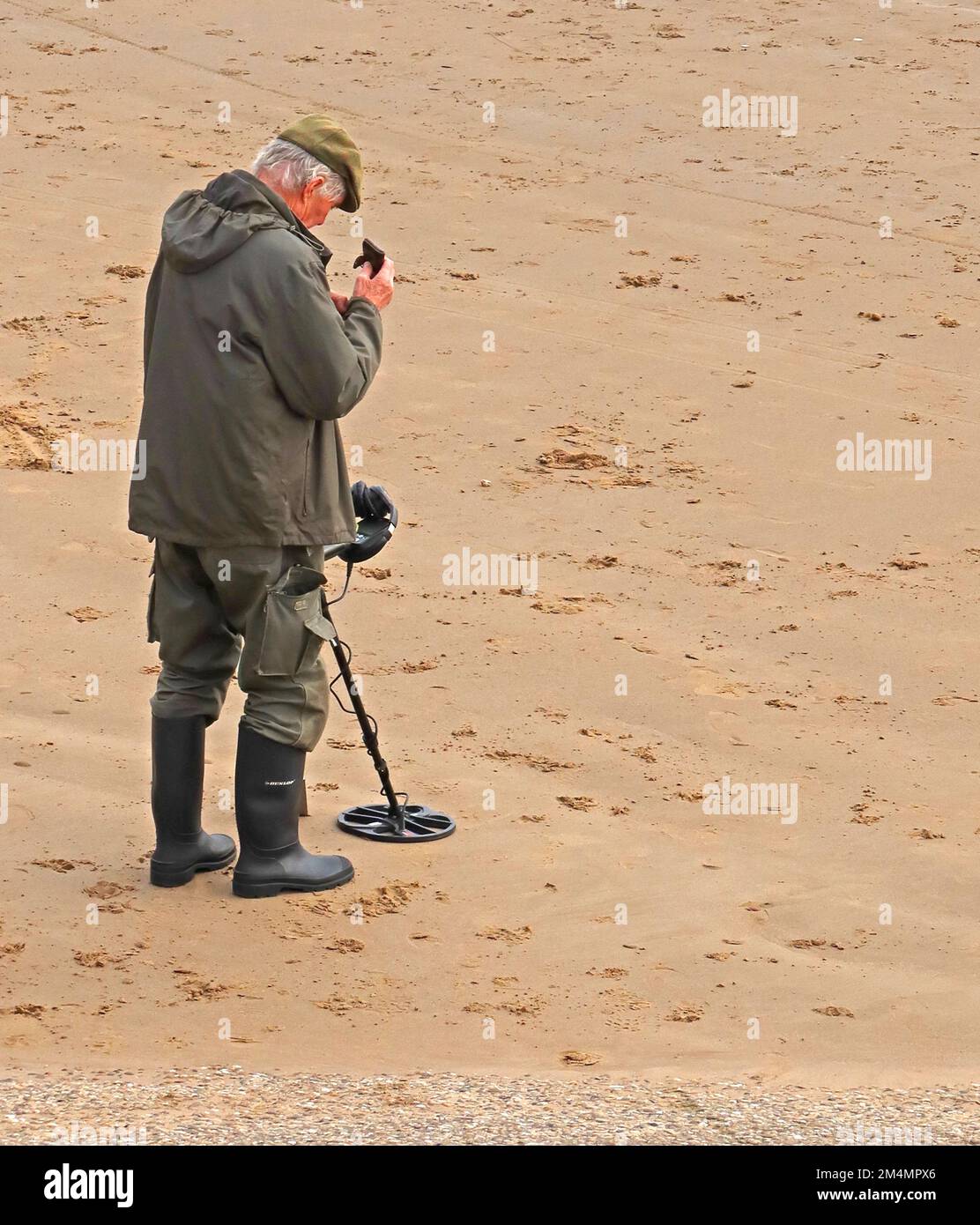 Ein Mann, der einen Metalldetektor benutzt, am Strand, in der Nähe von Filey, North Yorkshire, England, UK, YO14 9LA Stockfoto