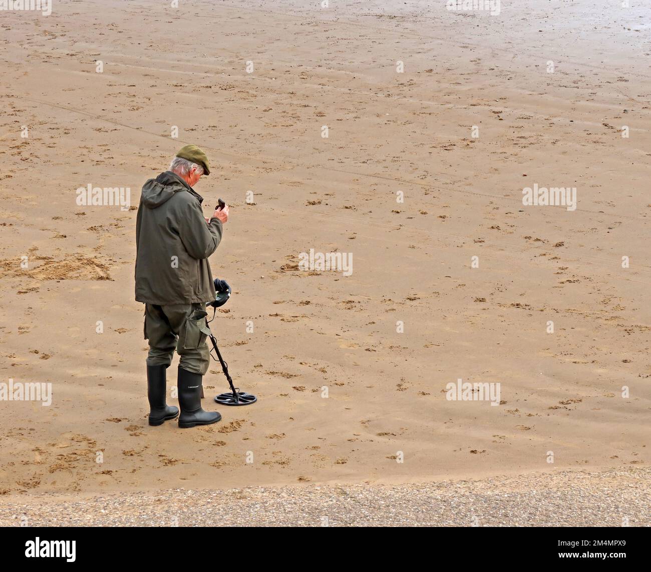 Ein Mann, der einen Metalldetektor benutzt, am Strand, in der Nähe von Filey, North Yorkshire, England, UK, YO14 9LA Stockfoto
