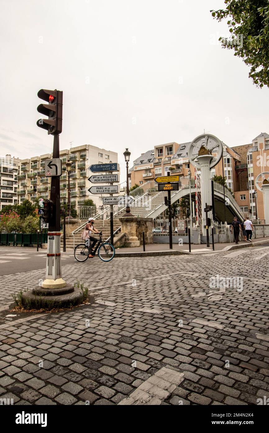 Paris Kopfsteinpflasterstraße mit der Pont de Flandre, Metallbrücke, Pont de la Rue de Crimée im Hintergrund. Die Brücke nach unten, damit die Fahrzeuge fahren können Stockfoto