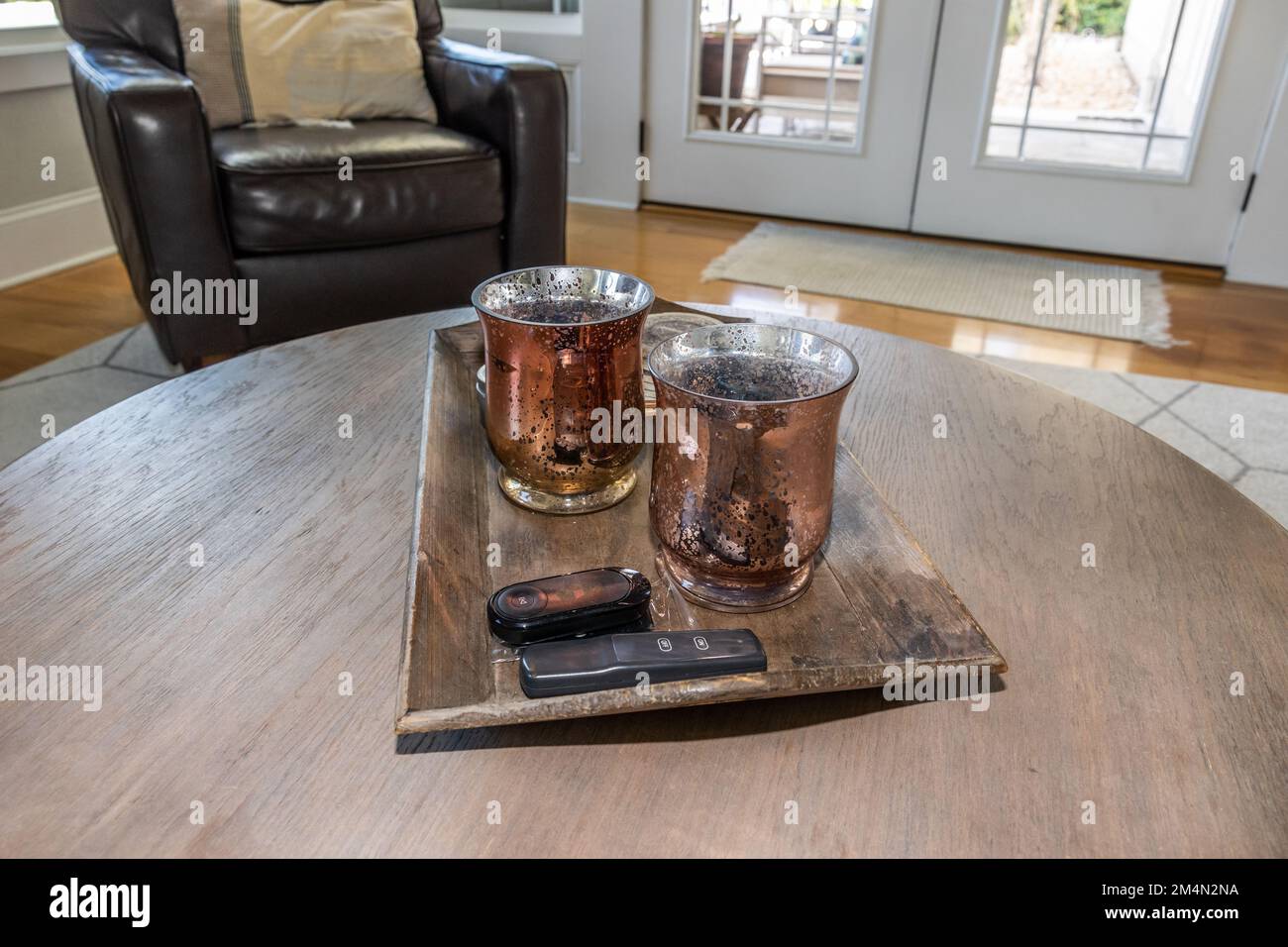 Ein Paar passende Kerzen, die auf einem Tablett mit Fernbedienung auf einem Couchtisch als Wohnzimmerdekoration sitzen Stockfoto