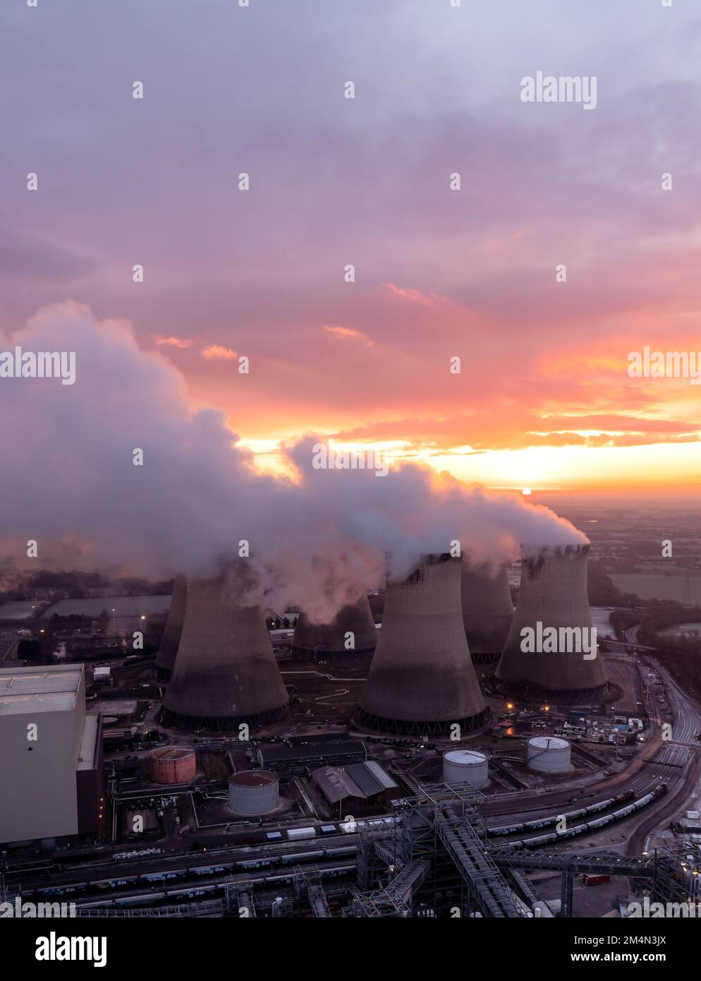 Luftaufnahme von schmutzigen Kohlekraftwerken, die die Atmosphäre bei Sonnenuntergang mit Kohlendioxidemissionen verschmutzen Stockfoto