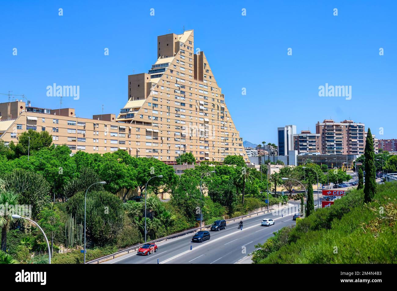 Ein Apartmentgebäude mit ungewöhnlicher Pyramidenform steht an einer geschäftigen Straße oder Straße in Alicante City Stockfoto