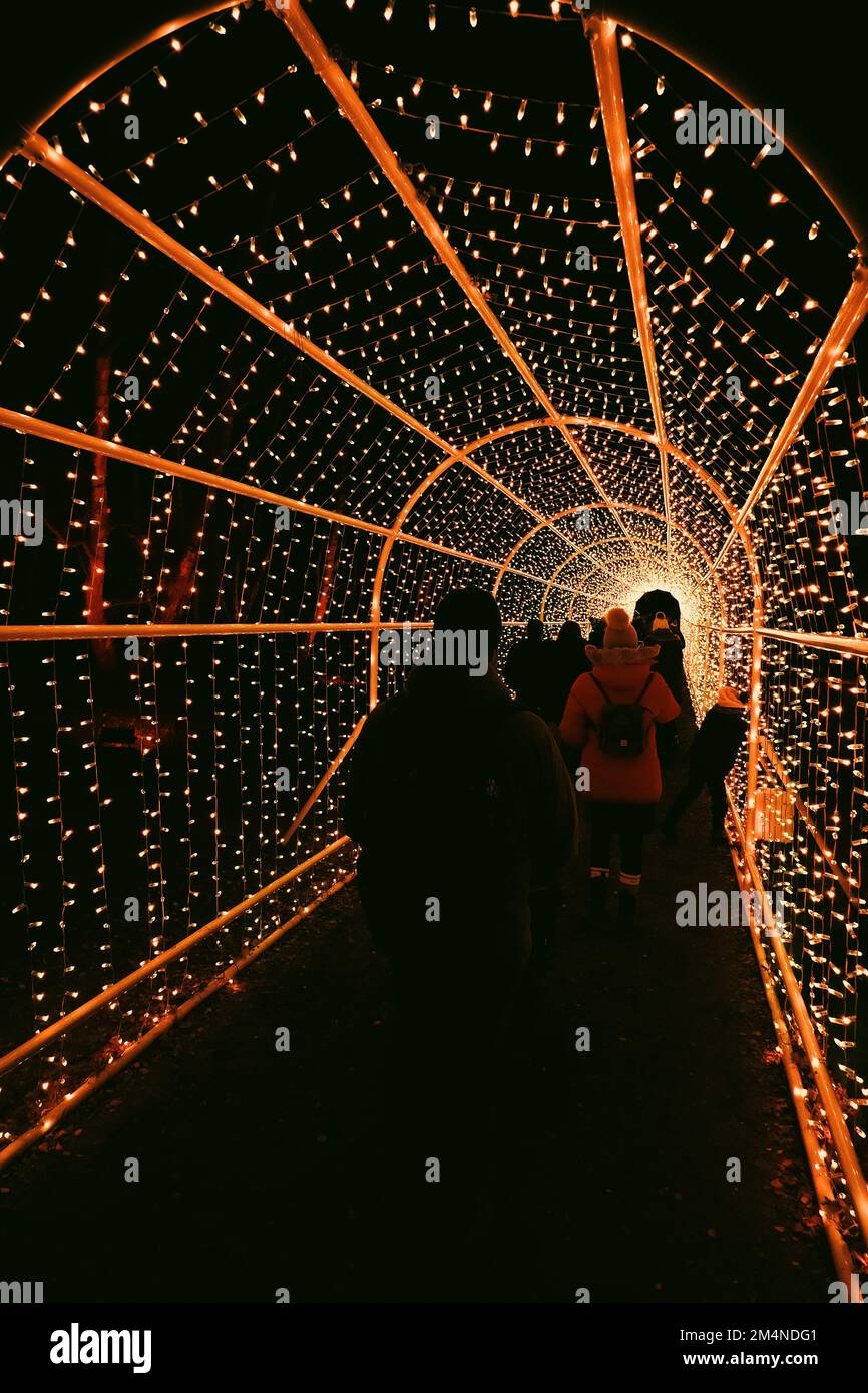 Eine Gruppe von Menschen geht nachts durch einen Lichttunnel. Stockfoto