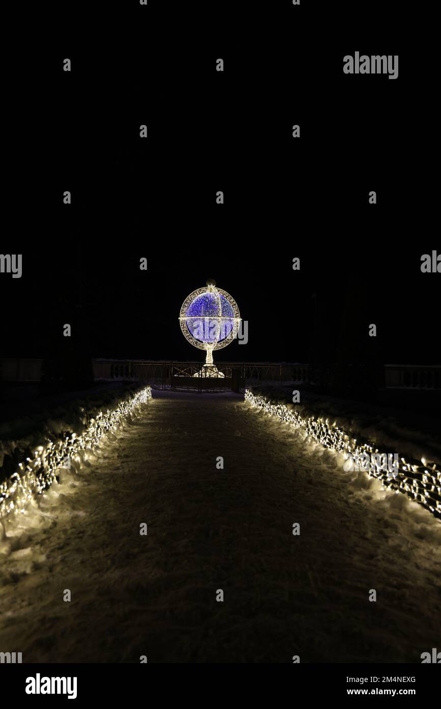 Der Weg zur Lichtkunst im Königlichen Garten des Lichts am Wilanów in Polen an einem dunklen Winterabend, der eine Armillarsphäre darstellt Stockfoto