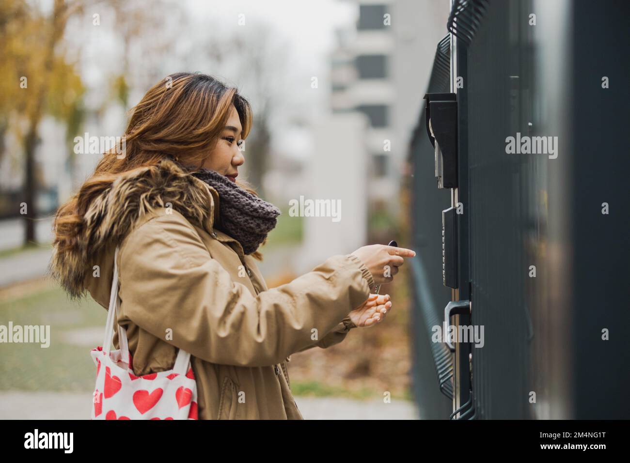 Junge Frau, die Code am Tor in der Stadt eingibt Stockfoto