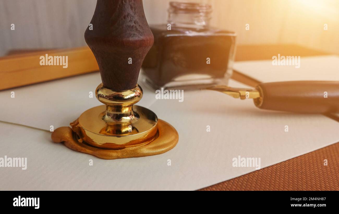 Authentischer offizieller Luxusbrief mit goldenem Siegel-Wachsstempel. Schreiben eines Briefes mit einem alten, klassischen Füllfederhalter, der in Tinte und Wachsstempel getaucht ist. Stockfoto