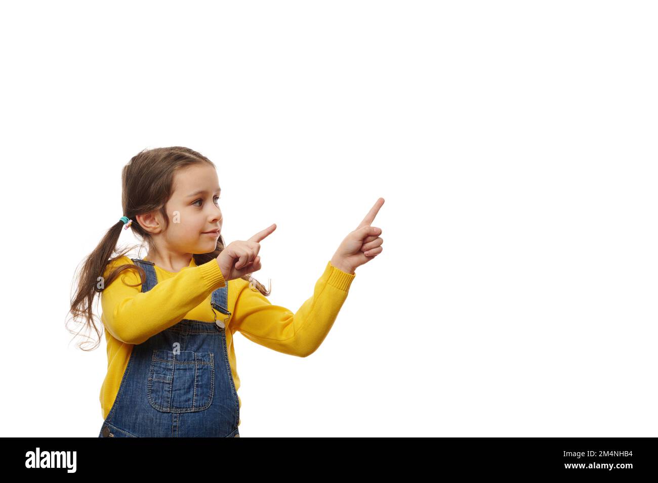 Kaukasisches, süßes kleines Mädchen mit zwei Pferdeschwanzen, Zeigefinger und Werbetexten. Stockfoto