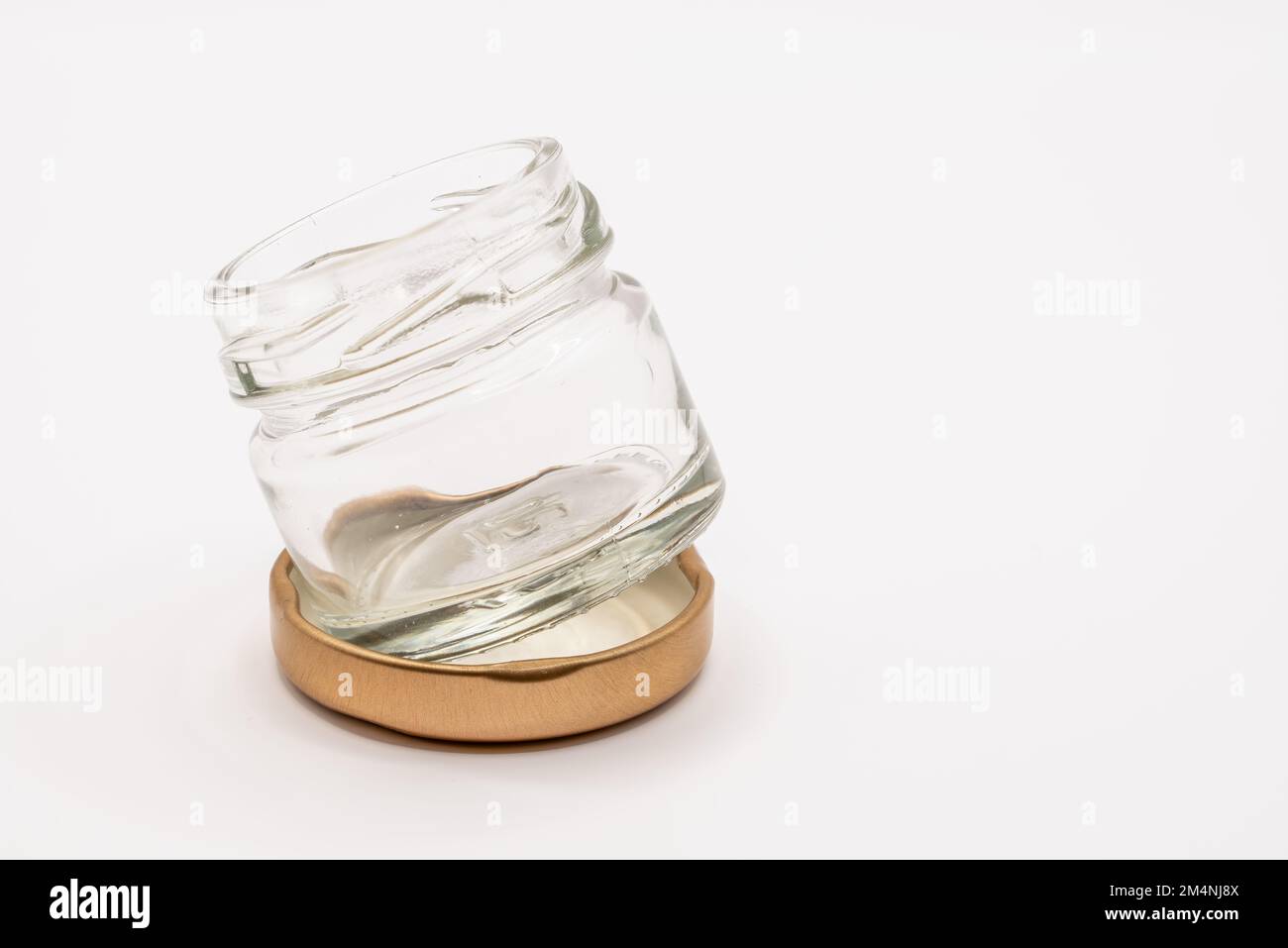 Nahaufnahme eines kleinen leeren Glasbehälters mit einem bronzefarbenen Metalldeckel Stockfoto