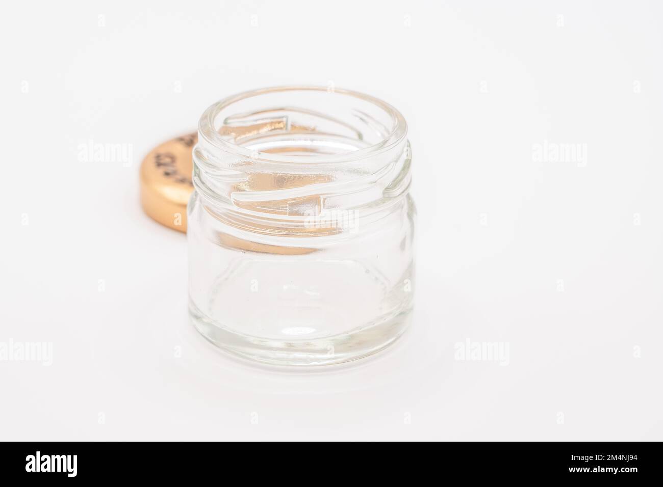 Nahaufnahme eines kleinen leeren Glasbehälters mit einem bronzefarbenen Metalldeckel Stockfoto