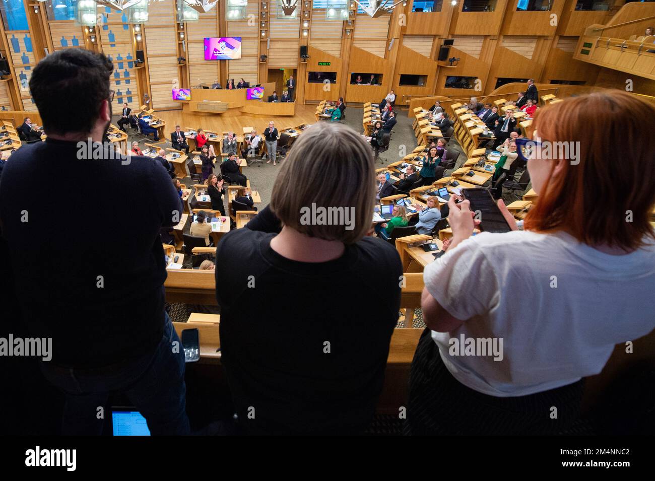 Edinburgh, Schottland, Großbritannien. 22. Dezember 2022. ABBILDUNG: Pro-Trans-Rechtler des Gesetzentwurfs feiern, nachdem die Ankündigung gemacht wurde, dass das Gesetz offiziell verabschiedet wurde. Sie jubeln und bedanken sich bei den MSPs unten im Saal, die ihrerseits reagieren, indem sie ihren Stuhl in Richtung Galerie richten und auf sie verzichten. Reaktionen in der Diskussionskammer nach Verabschiedung des Gesetzentwurfs zur Reform der Geschlechteranerkennung (Schottland) in Phase 3. Kredit: Colin D Fisher Kredit: Colin Fisher/Alamy Live News Stockfoto