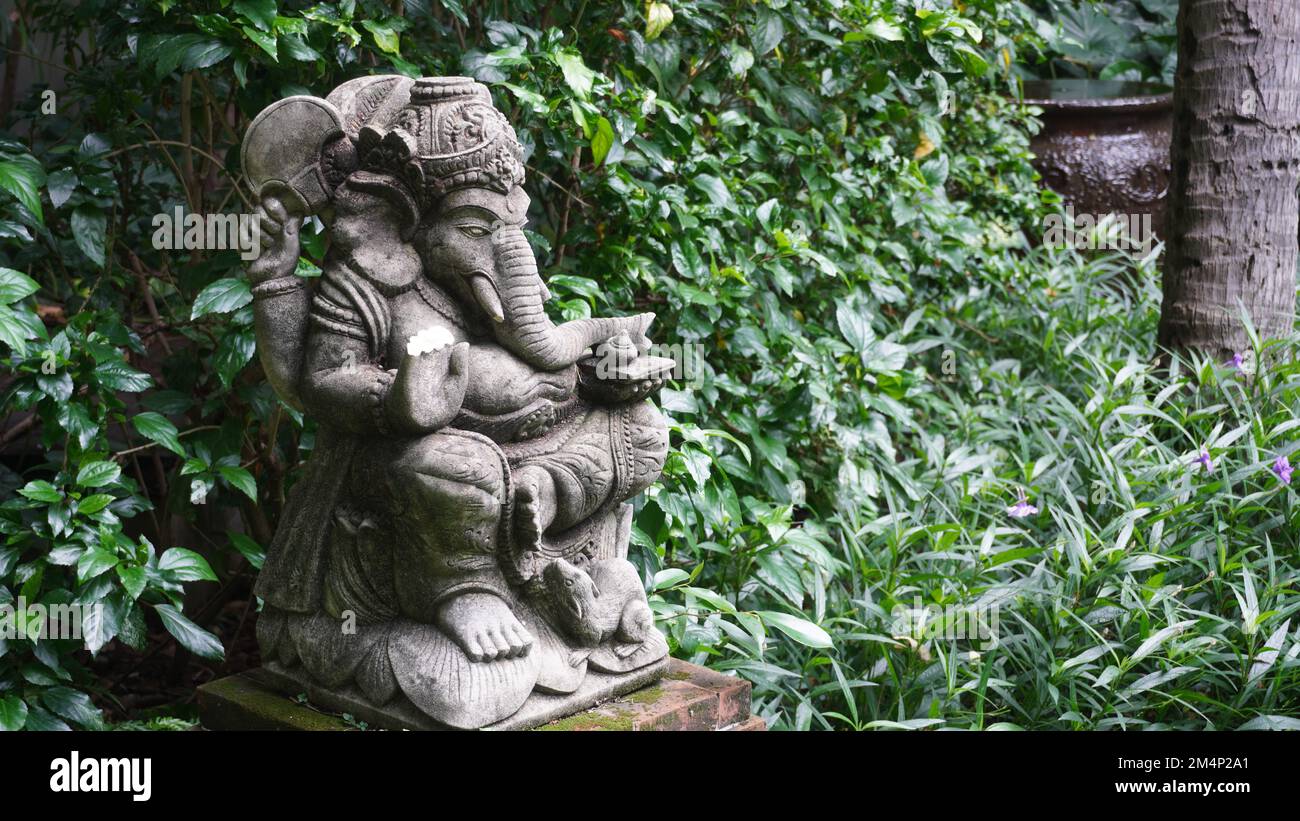 Ruhiger, ruhiger öffentlicher Park mit Statue auf einem riesigen alten Baum. Grüne Umgebung, geeignet für Entspannung und Meditation Stockfoto