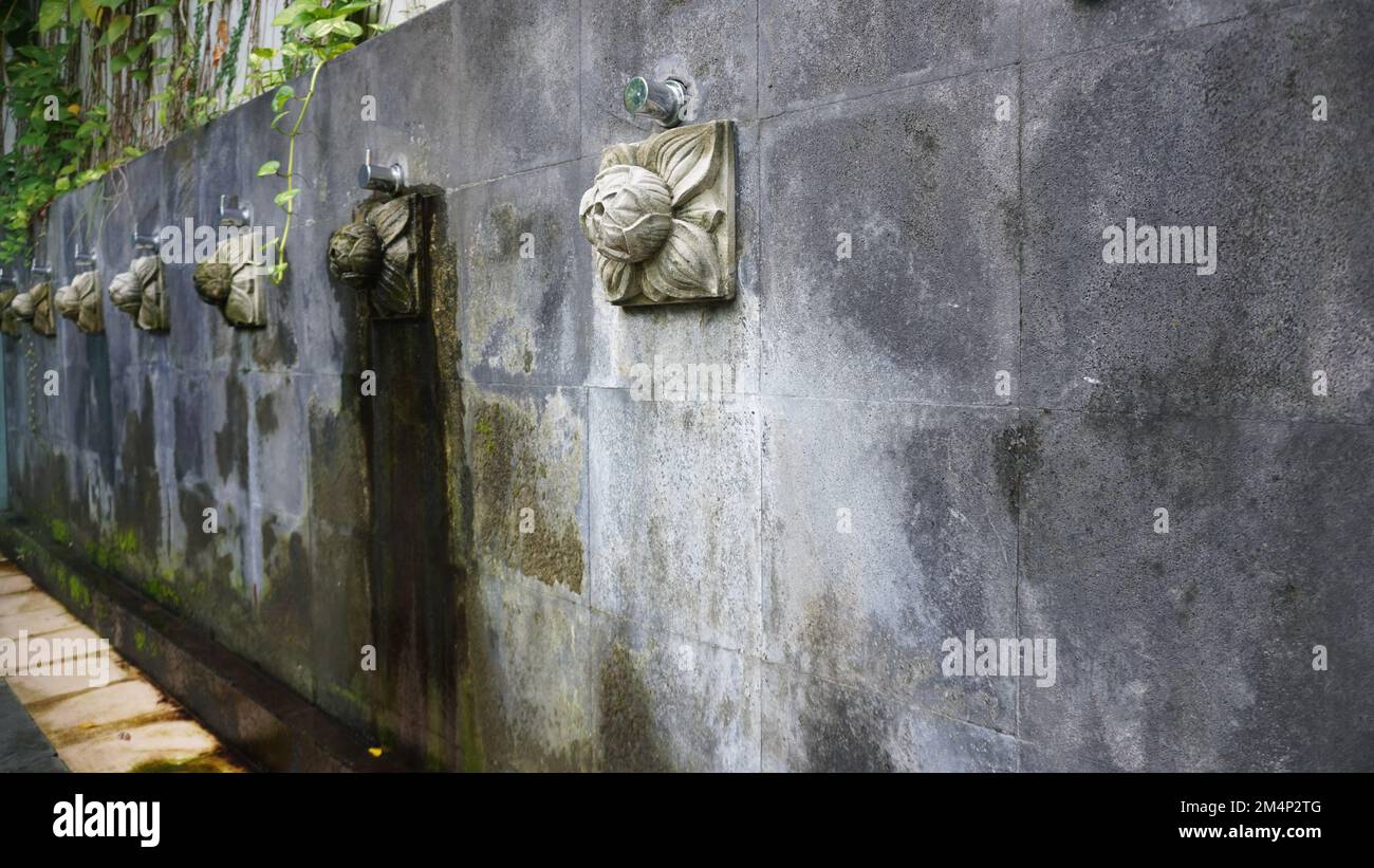 Künstlerischer Duschwasserbrunnen von der Steinwand. Zierhähne klebten an einer Steinwand, normalerweise zum Waschen von Hand, Fuß und Gesicht Stockfoto