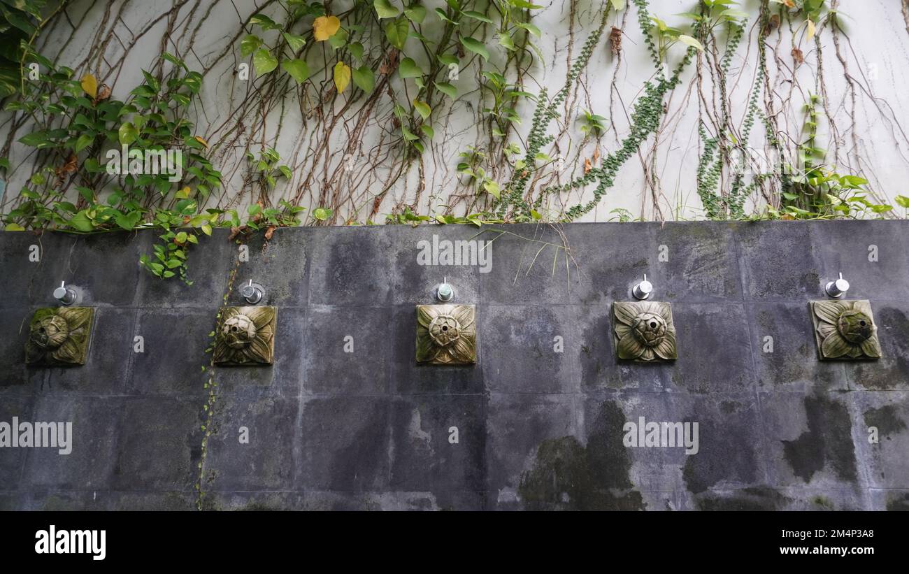 Künstlerischer Duschwasserbrunnen von der Steinwand. Zierhähne klebten an einer Steinwand, normalerweise zum Waschen von Hand, Fuß und Gesicht Stockfoto