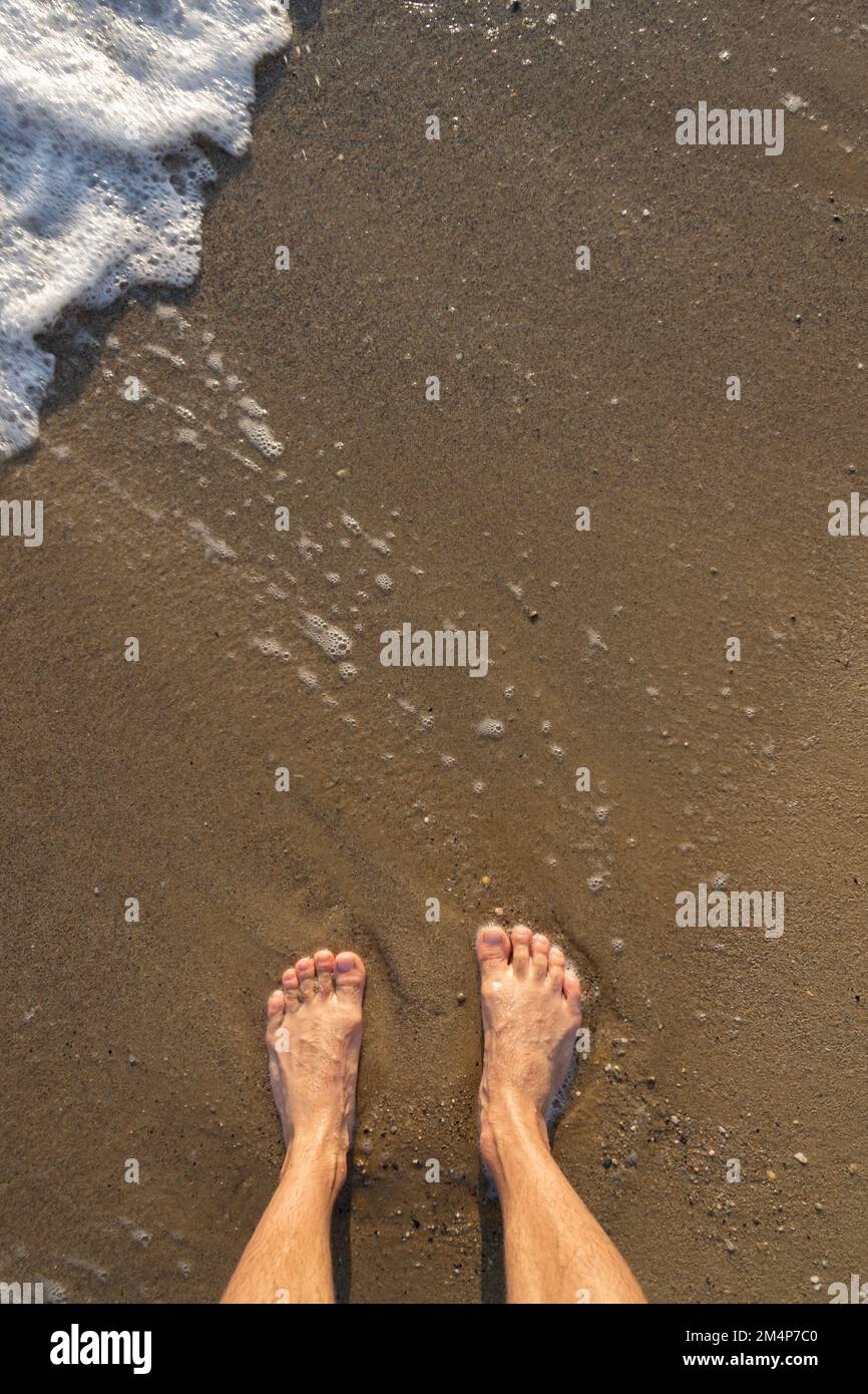 Menschliche Barfußfüße in nassem Sand am Meer, aktiv gesundes Wohnen Konzept Stockfoto