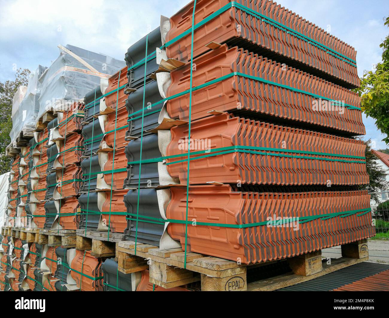 Neckargemuend, Deutschland: 7. Oktober 2022: Gepackte Stapel roter und anthrazitfarbener Dachziegel warten auf die Verarbeitung auf einer Baustelle Stockfoto