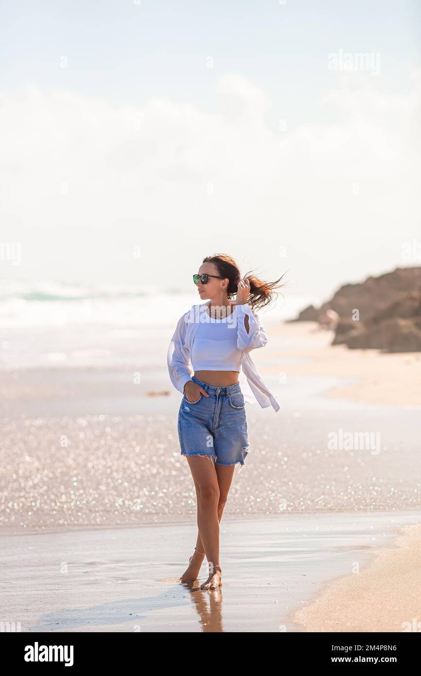 Junge glückliche Frau am Strand genießt ihren Sommerurlaub. Das Mädchen ist glücklich und ruhig in ihrem Aufenthalt am Strand Stockfoto