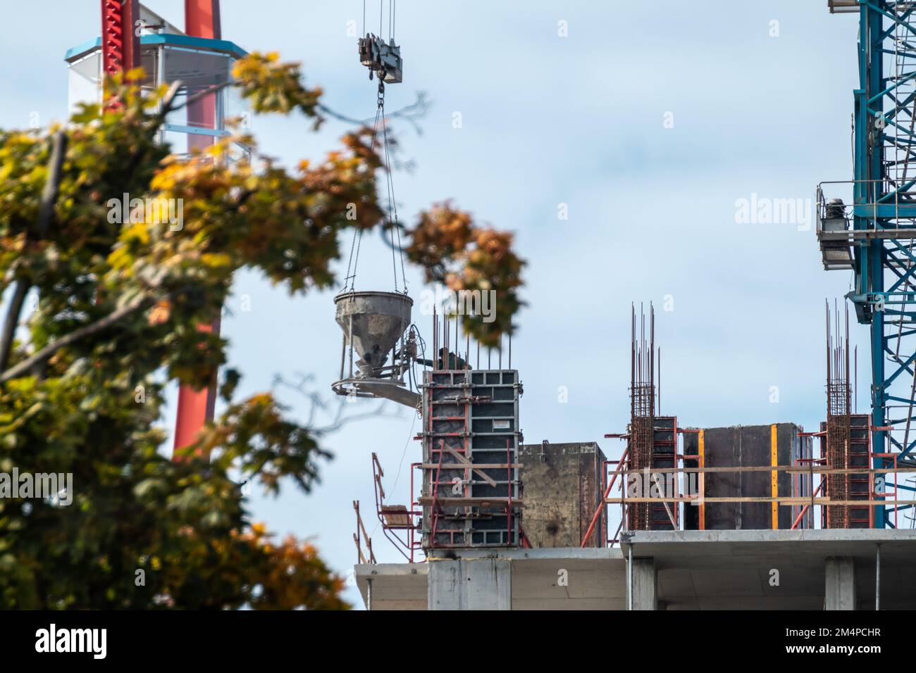 Kran mit Beton am Himmel über einer mehrstöckigen Baustelle Stockfoto