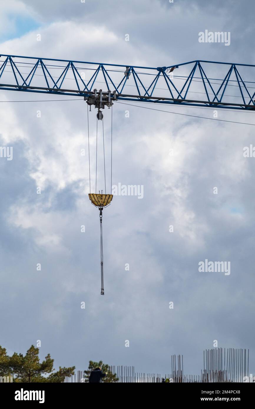 Blauer, hoher, überstehender Kranarm zum Heben großer schwerer Gewichte auf der Baustelle auf bewölktem, landschaftlich schönen Himmelshintergrund Stockfoto
