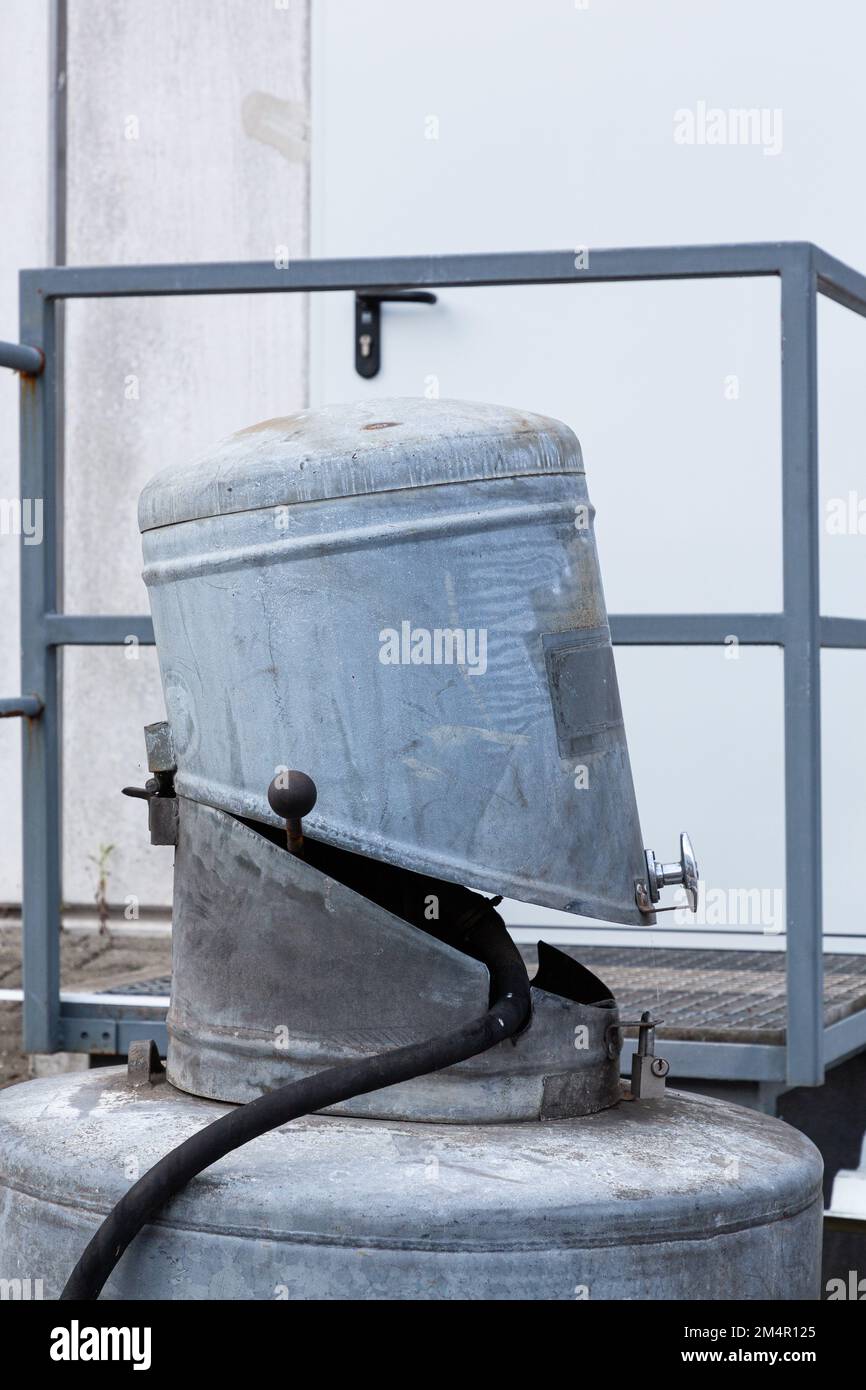 Ein kleiner runder Metallbehälter ist auf einem größeren montiert. Der kleinere ist offen wie ein Mund, aus dem ein Schlauch führt. Stockfoto