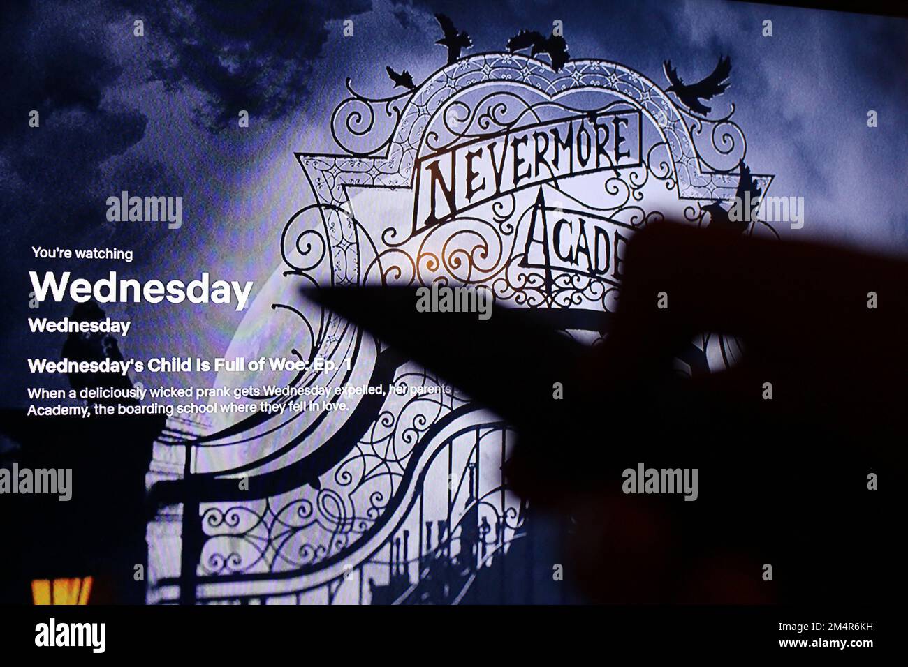 Die Netflix App auf dem fernsehbildschirm zeigt die Fernsehserie Mittwoch mit dem Schatten einer Fernsehfernbedienung. Stockfoto